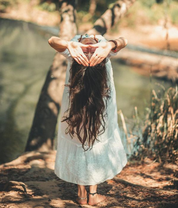 Woman in a calm yoga pose in a dark, serene environment.